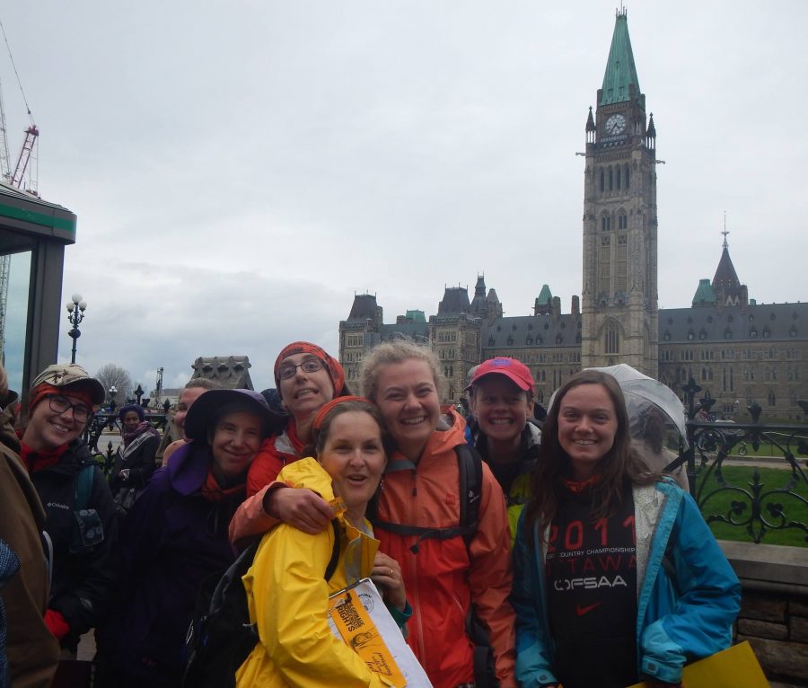 Erin Froese (centre) with a group of fellow smiling walkers in from the Parliament buildings in Ottawa, Ontario, having successfully reached their destination.