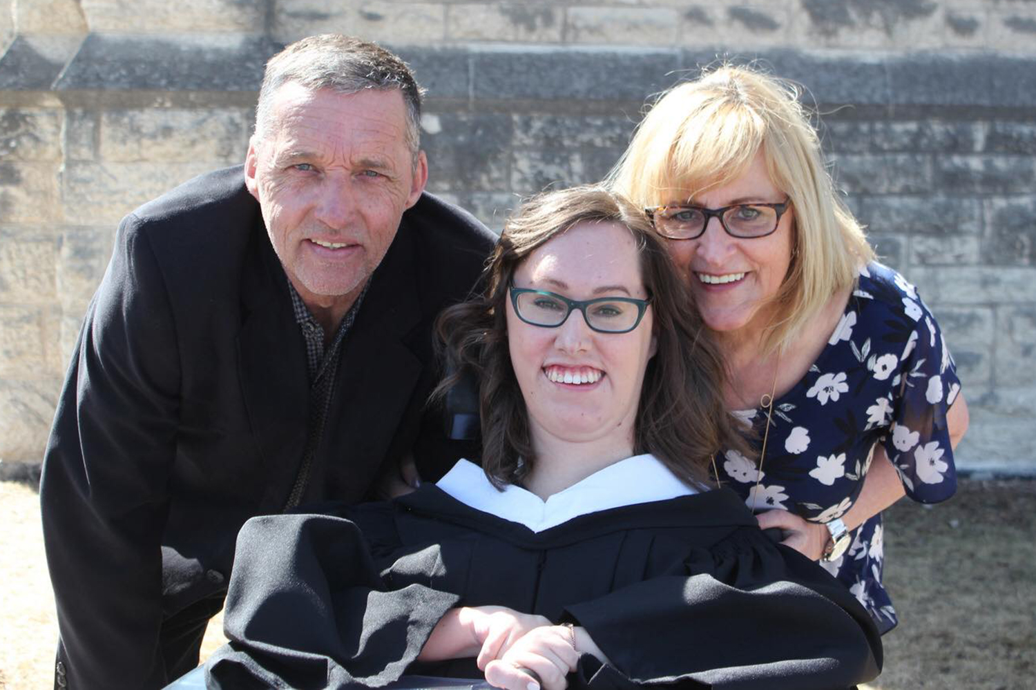 Cristina Waldner in her graduation gown surrounded by her parents on the day of her graduation from CMU.