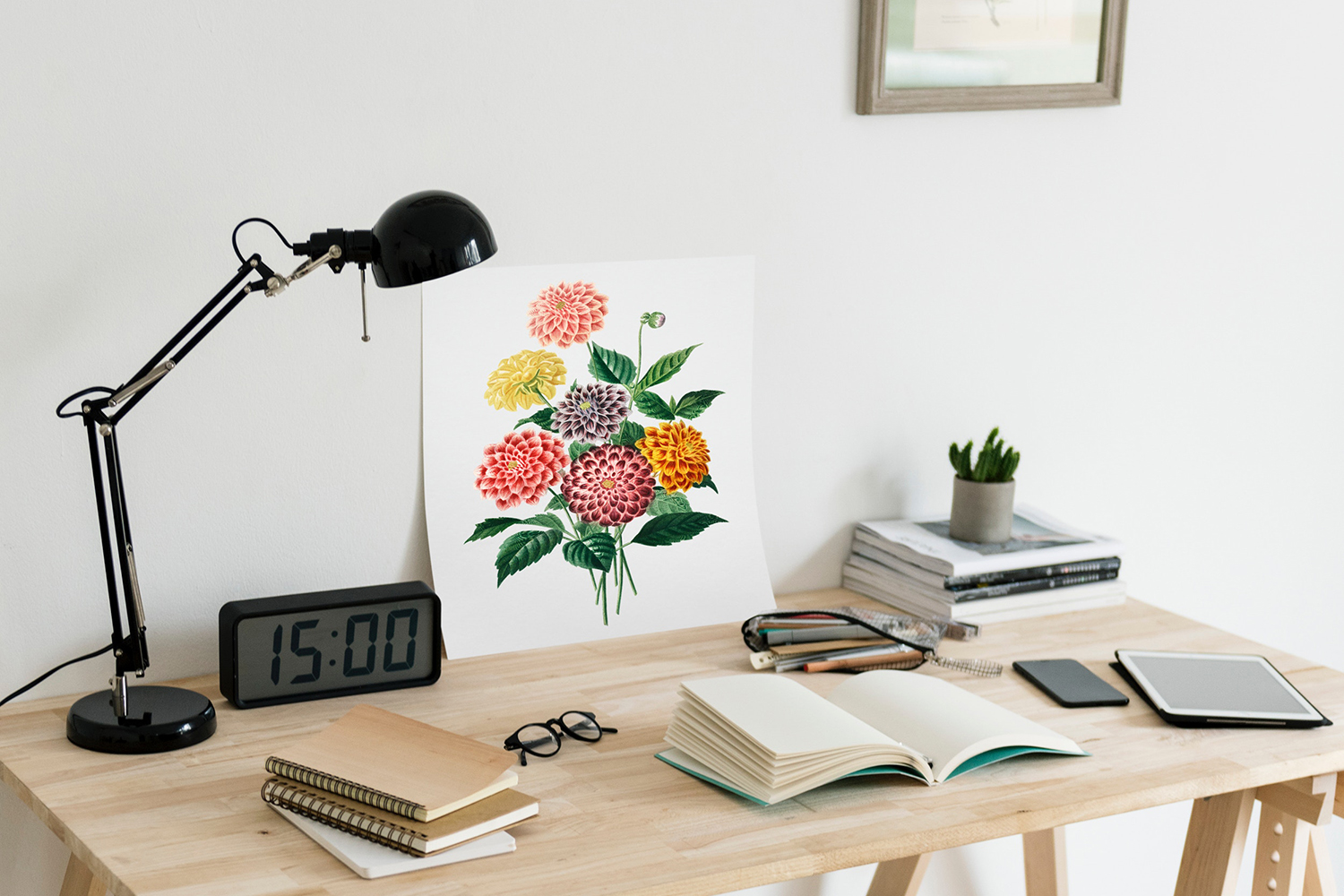 6 study tips — A modern wood desk topped with a black desk lamp, a large digital clock that reads "15:00", a colourful painting of a bouquet of flowers, several notebooks, a pair of glasses, a pencil case with highlighters tumbling out, a cell phone and tablet, and in the corner a stack of books topped by a small succulent plant.